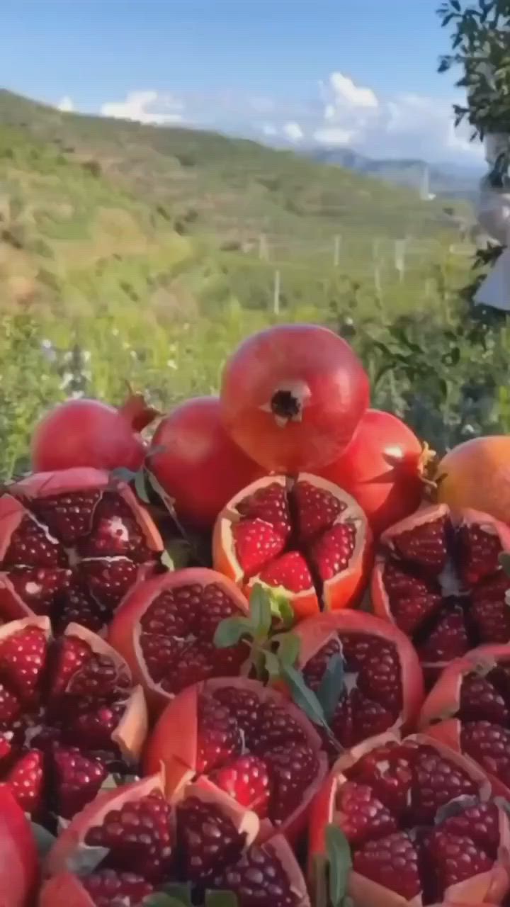 This may contain: pomegranates and other fruits are piled on top of each other outside