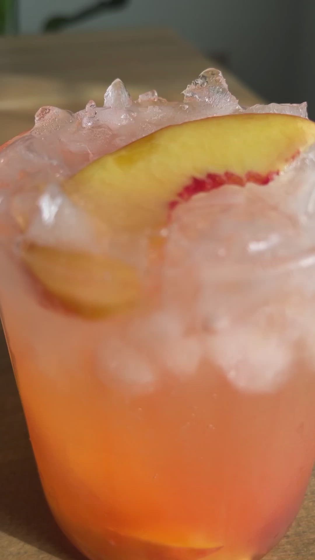 This may contain: a close up of a drink with ice and an apple on the rim, sitting on a table