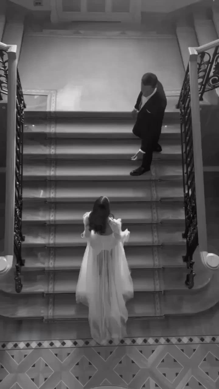 This may contain: the bride and groom are walking down the stairs at their wedding ceremony in black and white