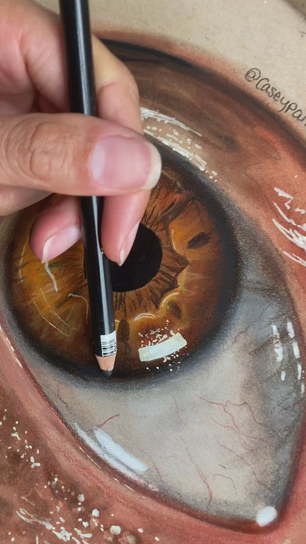 This may contain: a hand holding a pencil in front of an eye with water on the bottom and below it