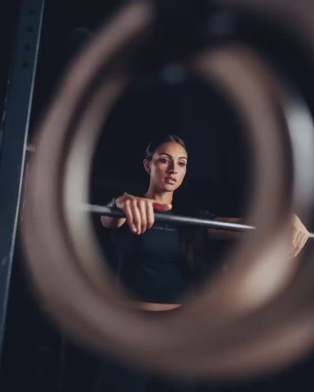 This may contain: a woman holding a bar in front of her face and looking at the camera through a circular lens