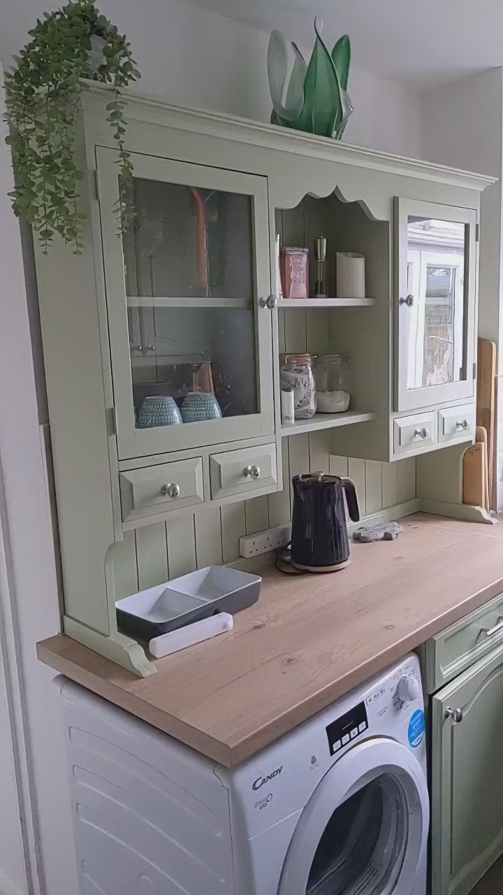 This may contain: a washer and dryer sitting in a kitchen next to a cabinet with glass doors