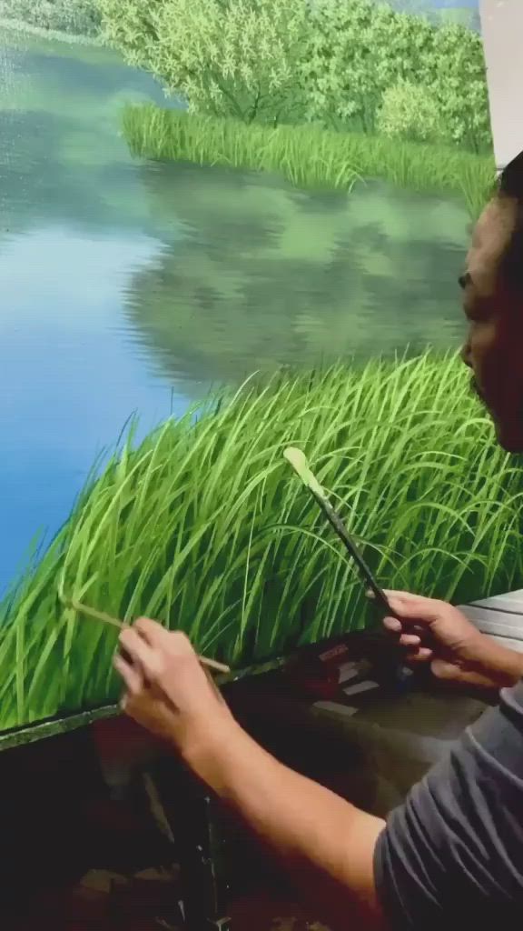 This may contain: a man is painting some grass by the water