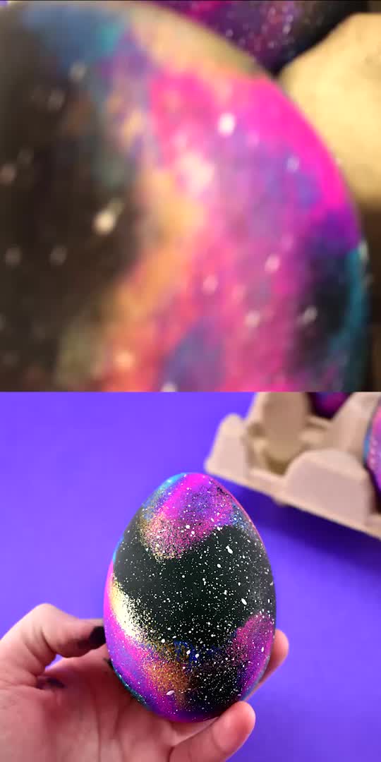 This may contain: someone is painting an easter egg with purple and blue paint on the outside, then it's covered in glitter