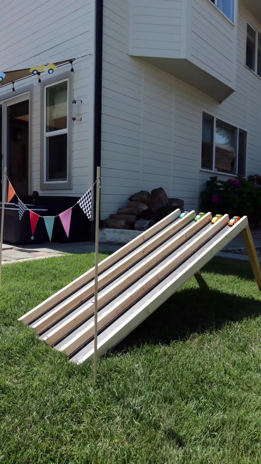 This may contain: an upside down wooden sled in the grass with bunting flags hanging from it