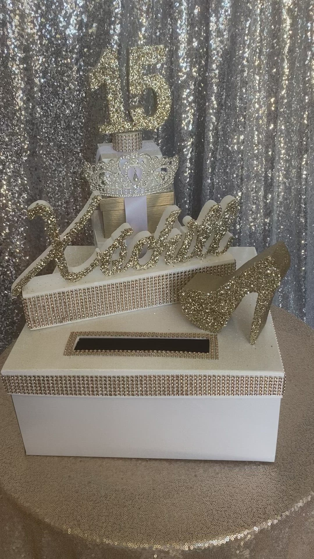 This may contain: there is a white box with gold decorations on the top and silver sequins around it