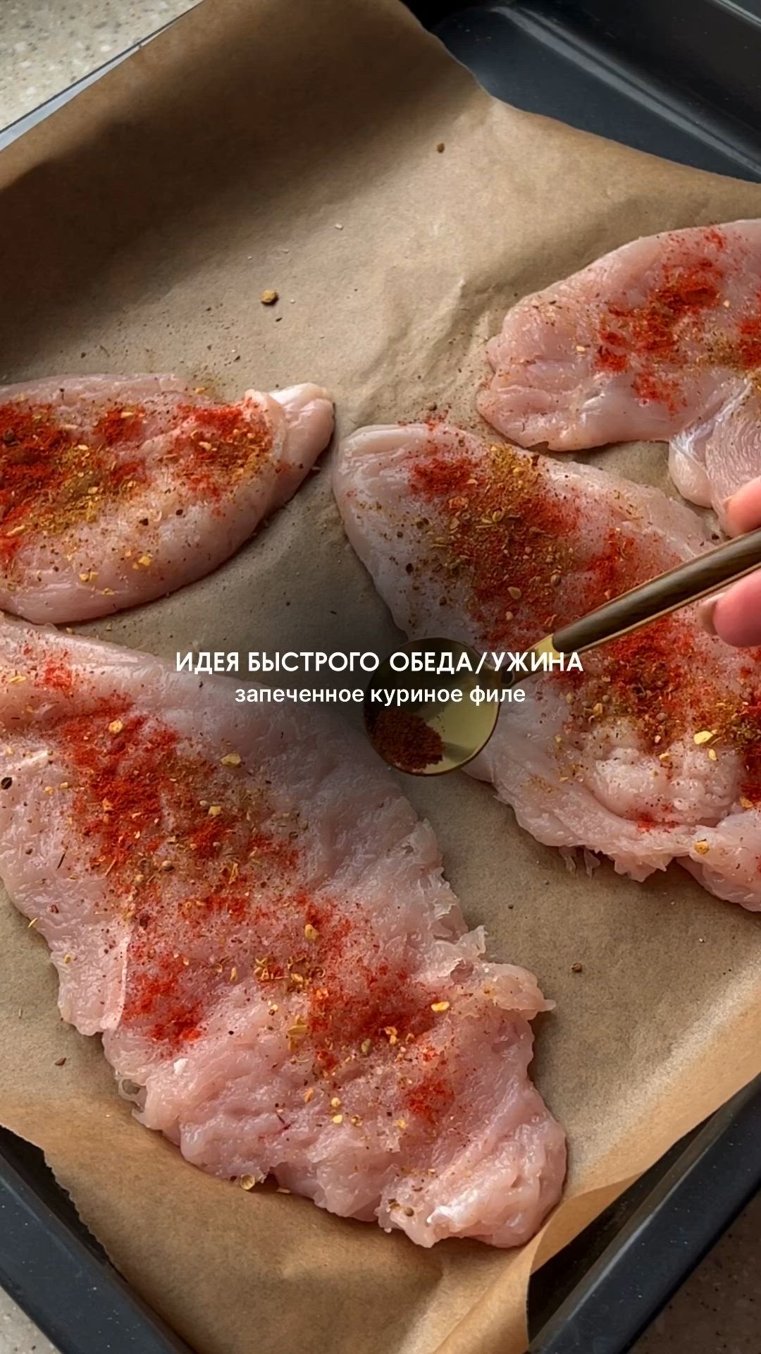 This may contain: a person holding a spoon over raw meat on a baking sheet with seasoning sprinkles