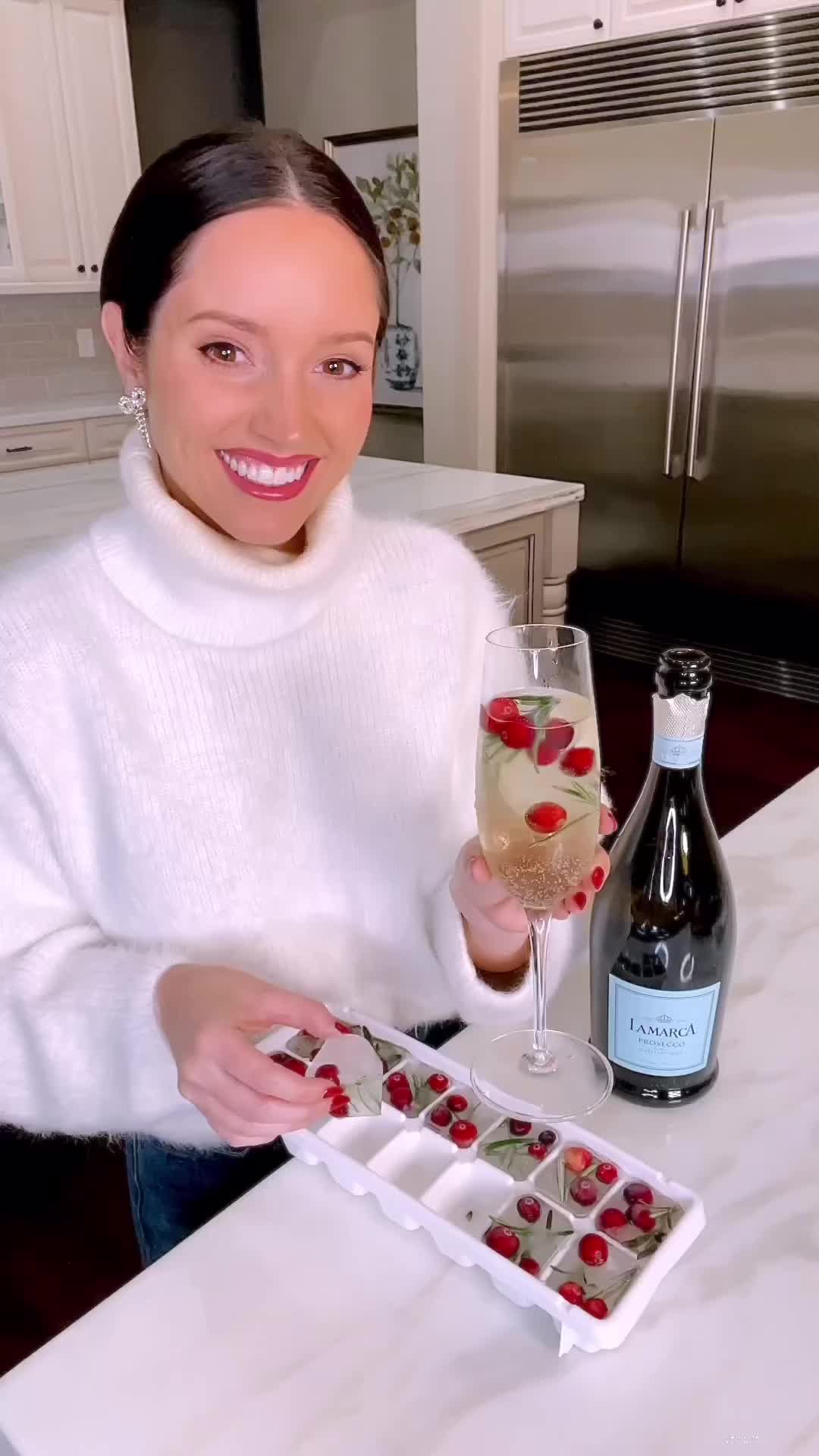 This may contain: a woman is holding a wine glass with cherries on it and ice cubes in front of her