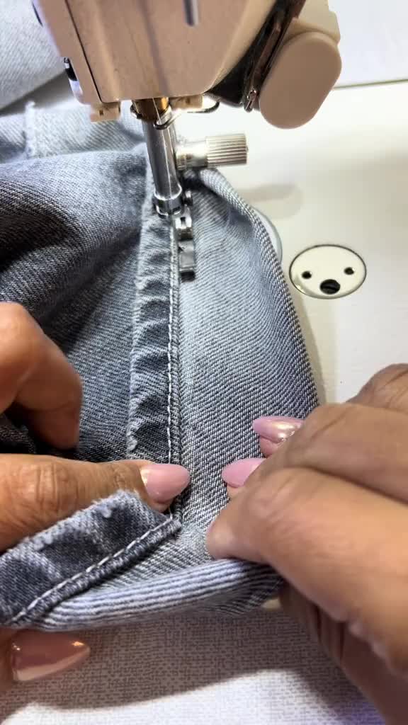 This may contain: someone is sewing on the jeans with a sewing machine