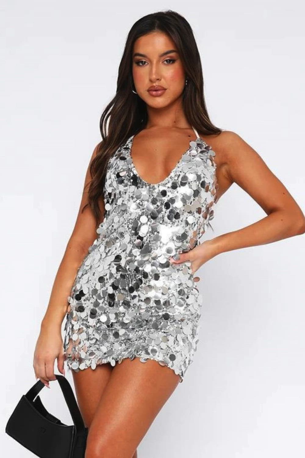 This contains: Turn heads in this glittery mini dress. Featuring an allover sequin design, a V-Neckline with halter straps, and a backless design, this mini dress is sure to make a statement. Perfect for parties or a night out, this show-stopping dress is sure to make you the center of attention.