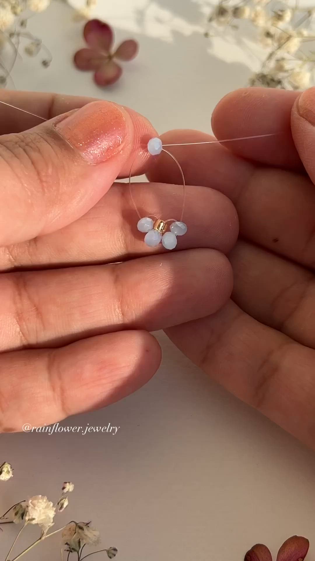 This may contain: two hands are holding small white flowers in their fingertipss and one hand is holding the other