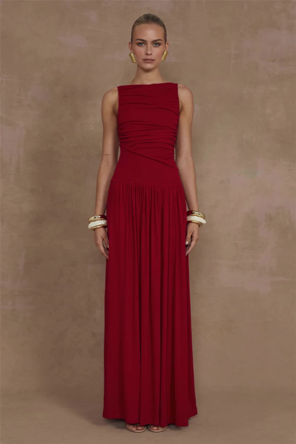 This contains: This elegant sleeveless maxi dress is a must-have addition to any woman's wardrobe. Featuring a solid boat neck and sexy ruched detailing, this dress is both fashionable and comfortable. Made with high-quality materials, it is perfect for any occasion and will make you stand out from the crowd.