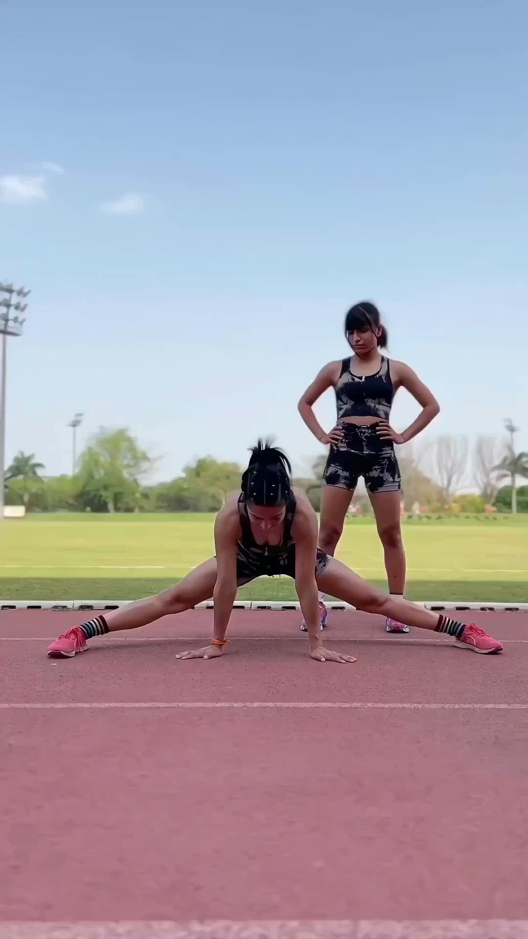 This may contain: two young women are doing push ups on a track with the words can't do full splits?