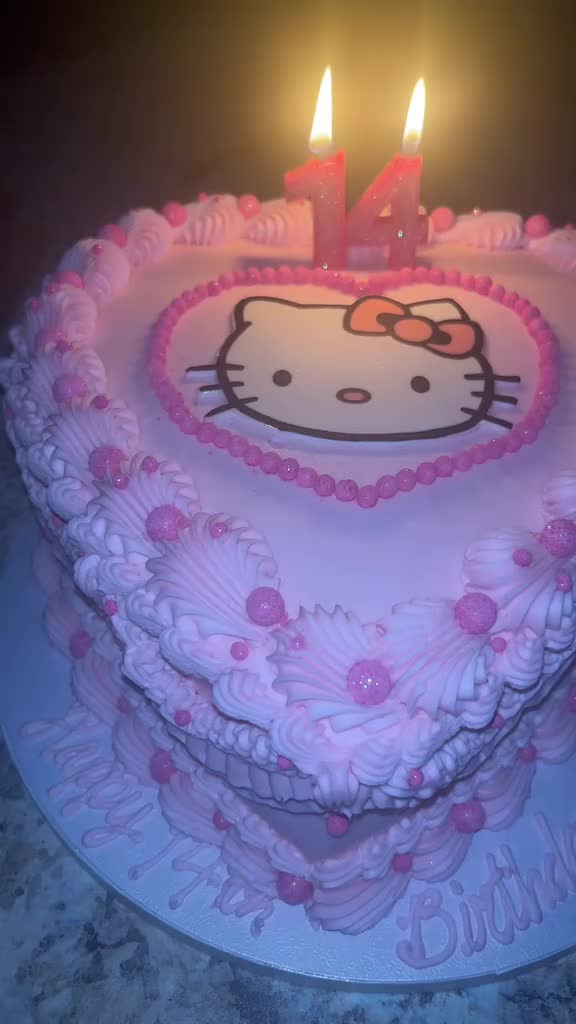 This may contain: a hello kitty birthday cake with candles in the shape of a heart