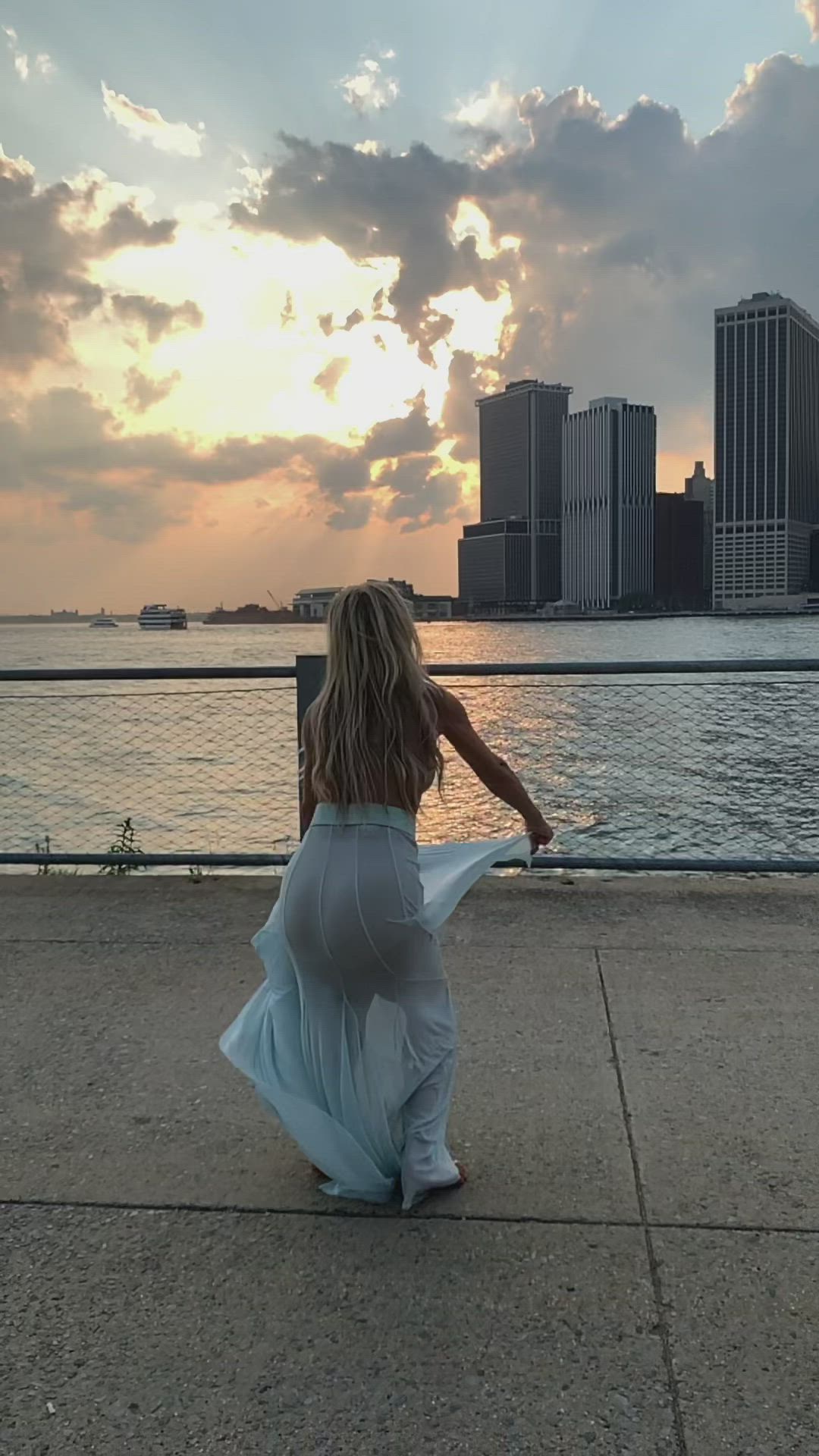 This may contain: a woman is jumping in the air with her arms spread out and she is wearing a white dress