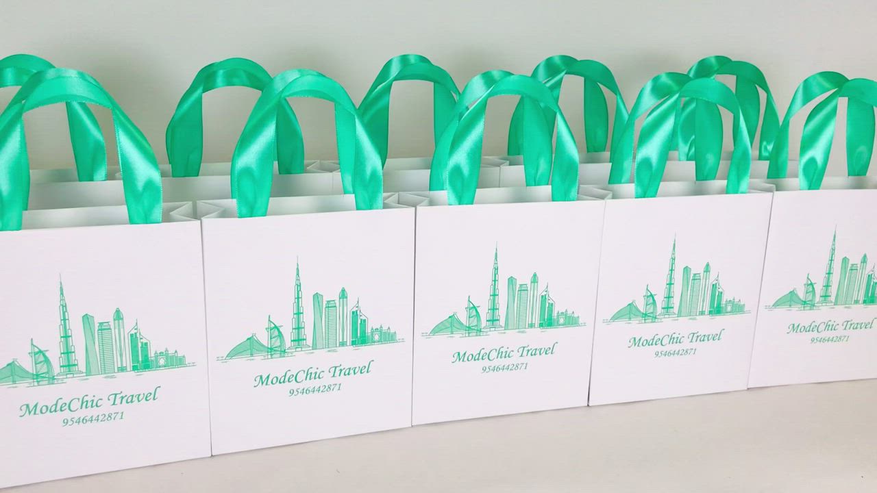 This may contain: six bags with green ribbons are lined up on a table in front of a white wall