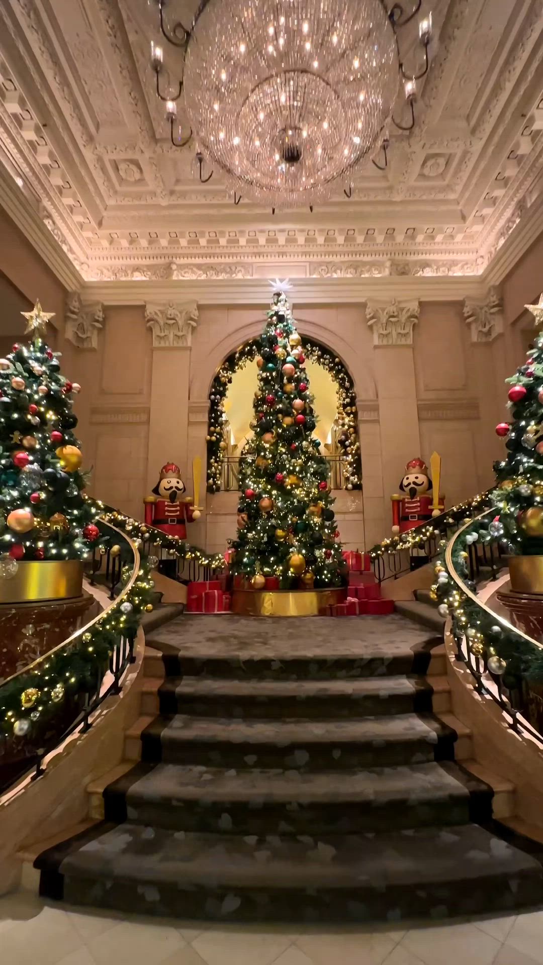 This may contain: a large christmas tree in the middle of a room with stairs and decorations around it