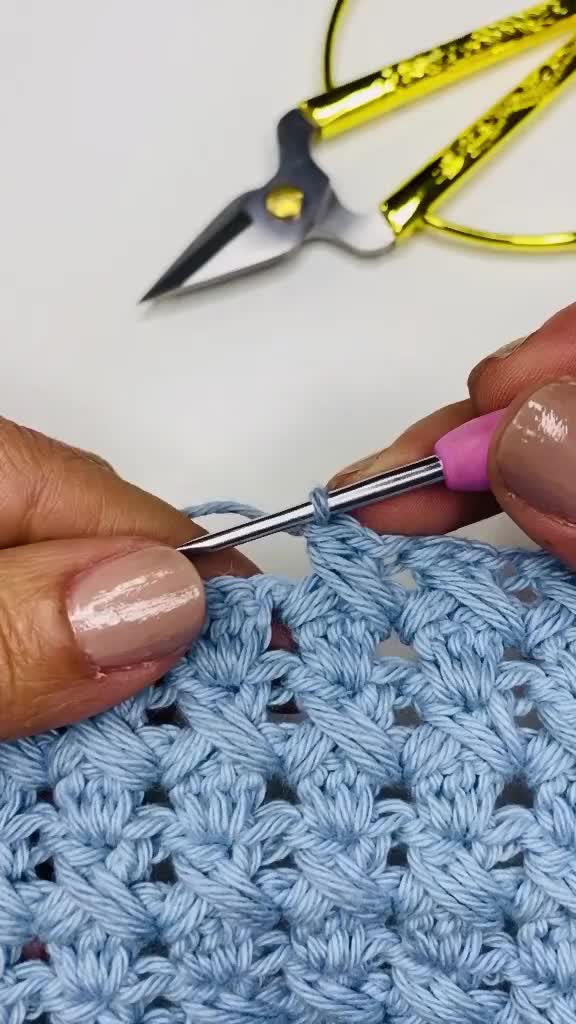 This may contain: someone is crocheting the stitchs with scissors