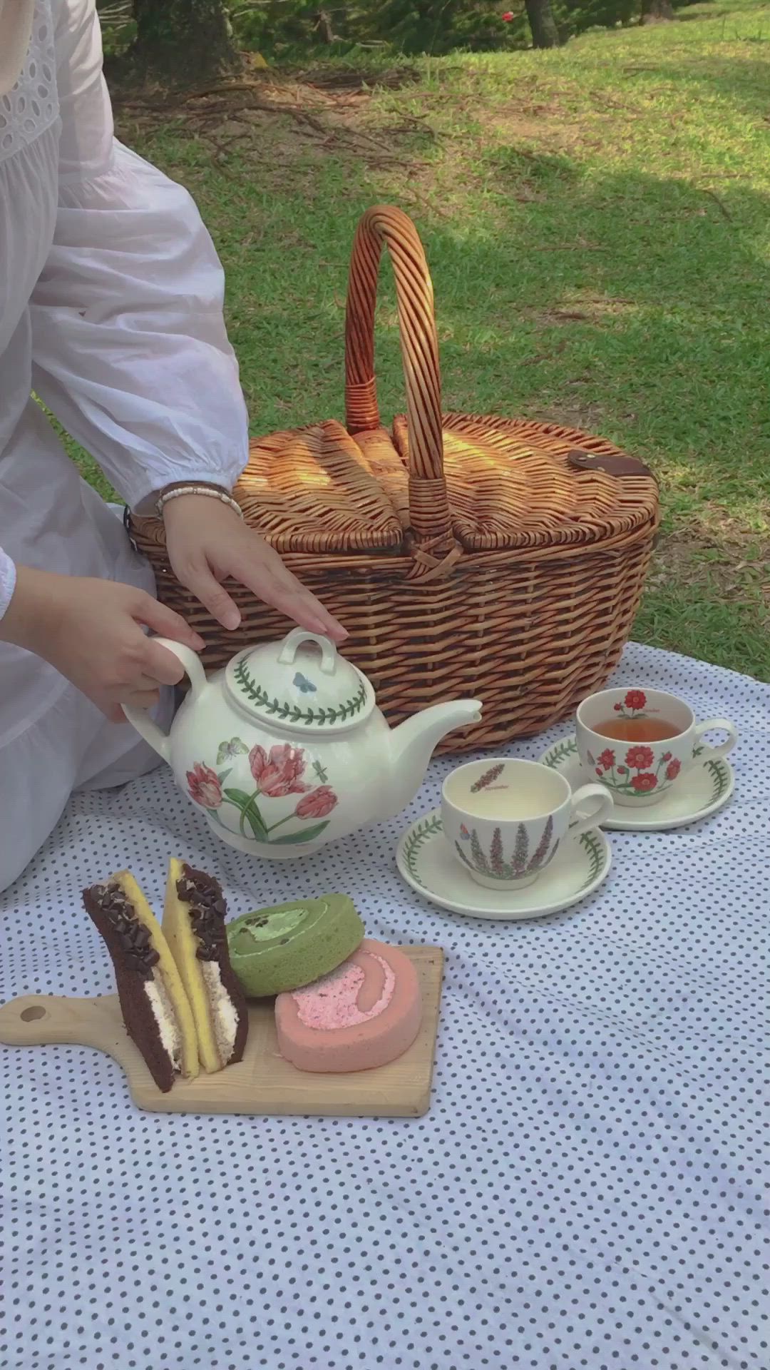 This may contain: a woman sitting at a picnic table with tea and pastries in front of her