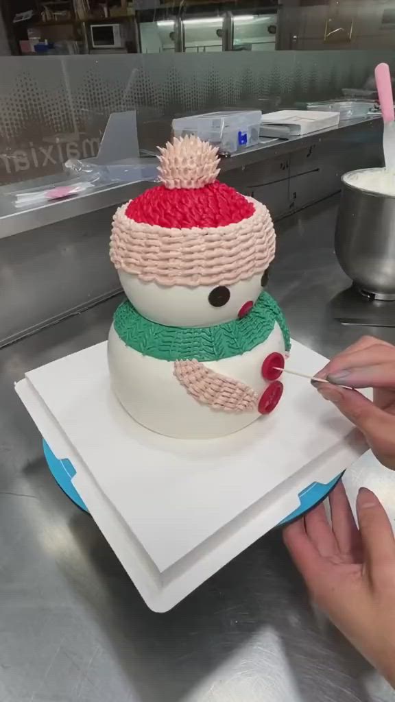 This may contain: a person is decorating a snowman cake