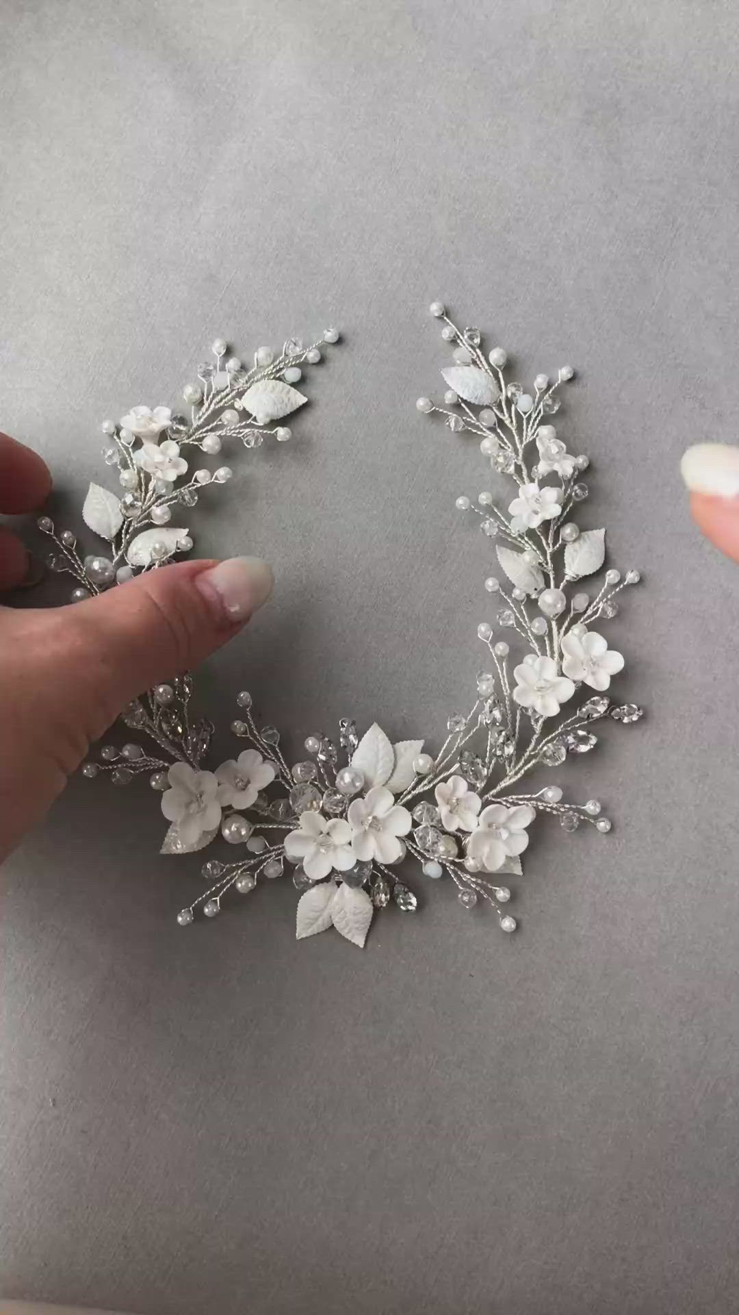 This may contain: someone is making a flower crown out of silver and white flowers on top of grey paper