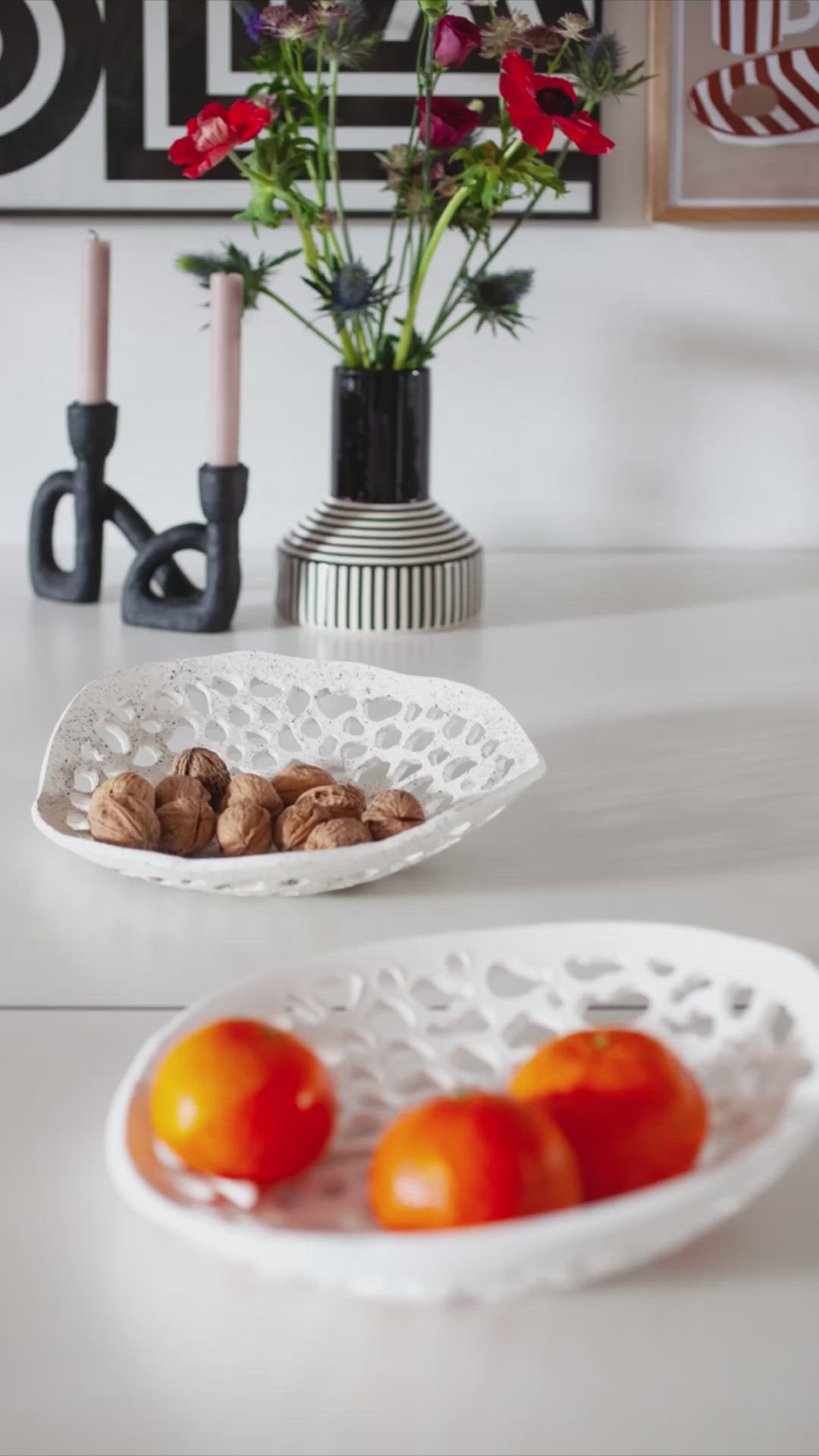 This may contain: two white bowls filled with fruit and nuts on top of a table next to flowers