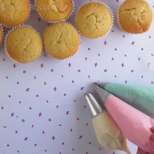 This may contain: cupcakes with pink and green frosting are arranged on a table