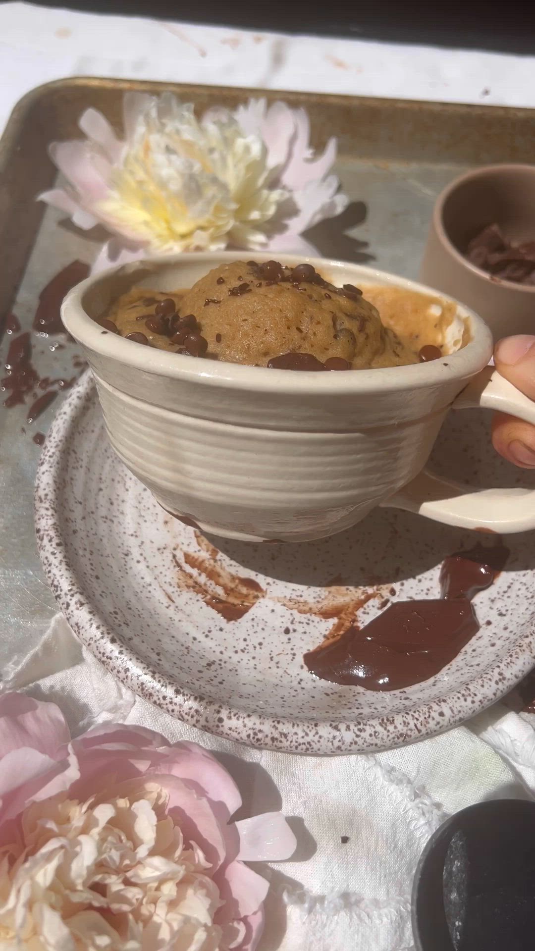 This may contain: a person holding a bowl filled with food on top of a table next to flowers