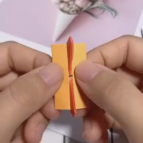 This may contain: two hands are holding an origami piece