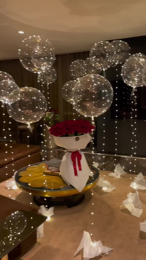 This may contain: some balloons are floating in the air on a table with white paper flowers and streamers