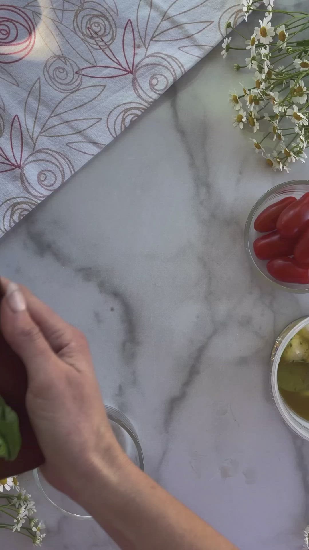 This may contain: someone is cutting tomatoes on a marble counter top with olives and peppers in small bowls