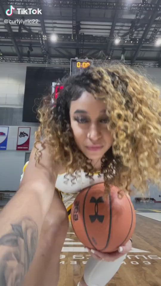 This may contain: a woman in white and yellow uniform holding a basketball