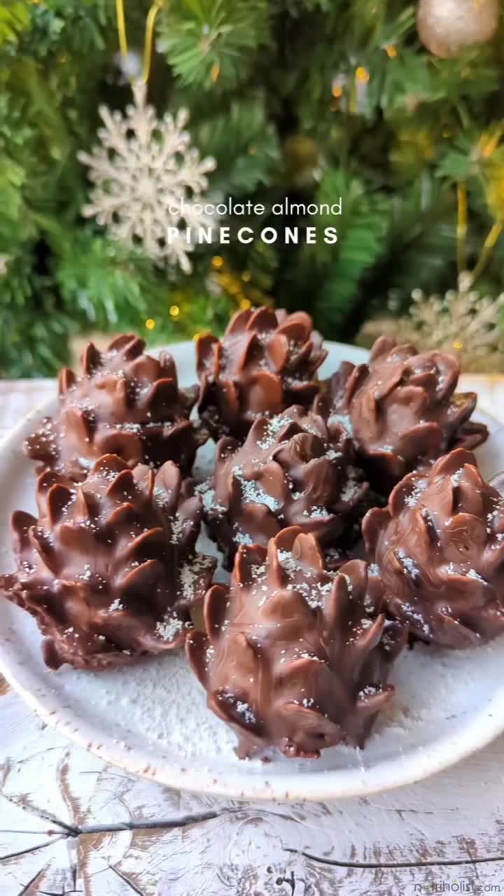 This may contain: chocolate almonds on a white plate next to a christmas tree with snowflakes