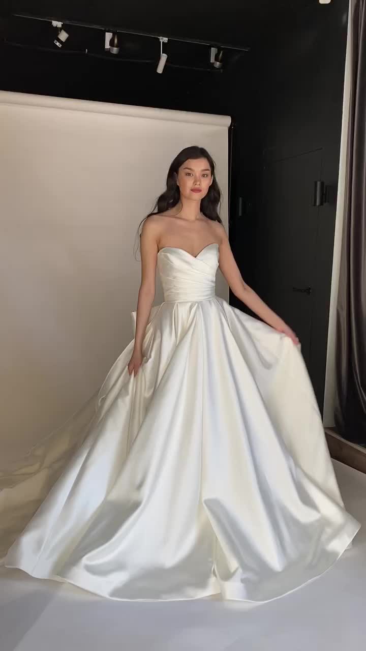 This contains: Off shoulders sweetheart neckline draped corset a-line satin fall romantic timeless wedding dress with long train