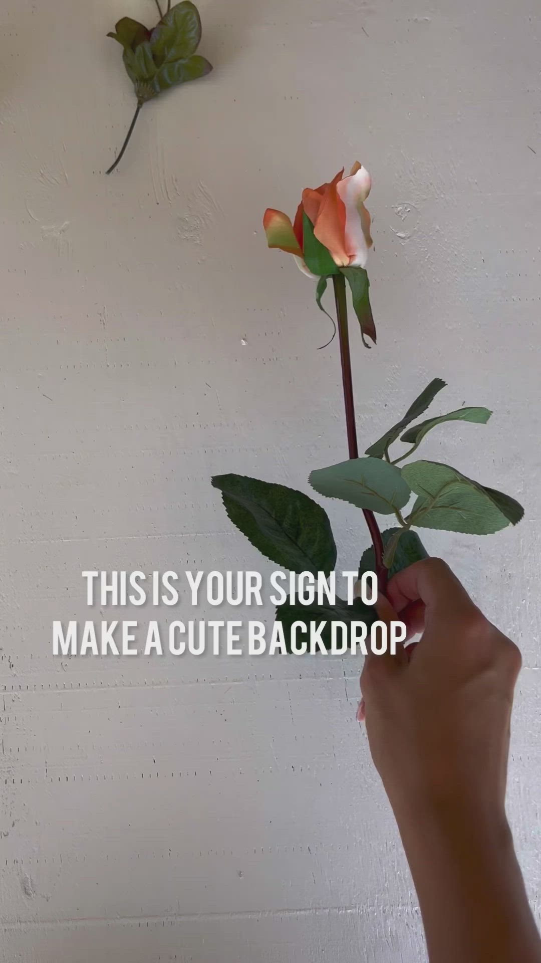 This may contain: a woman standing next to a chair in front of a wall with flowers on it