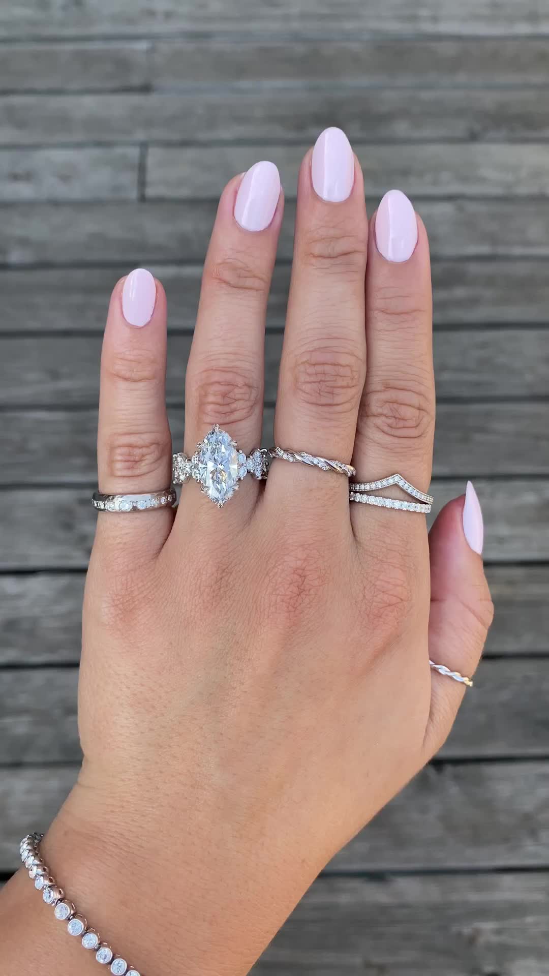 This may contain: a woman's hand with three different rings on her fingers and two diamond bracelets