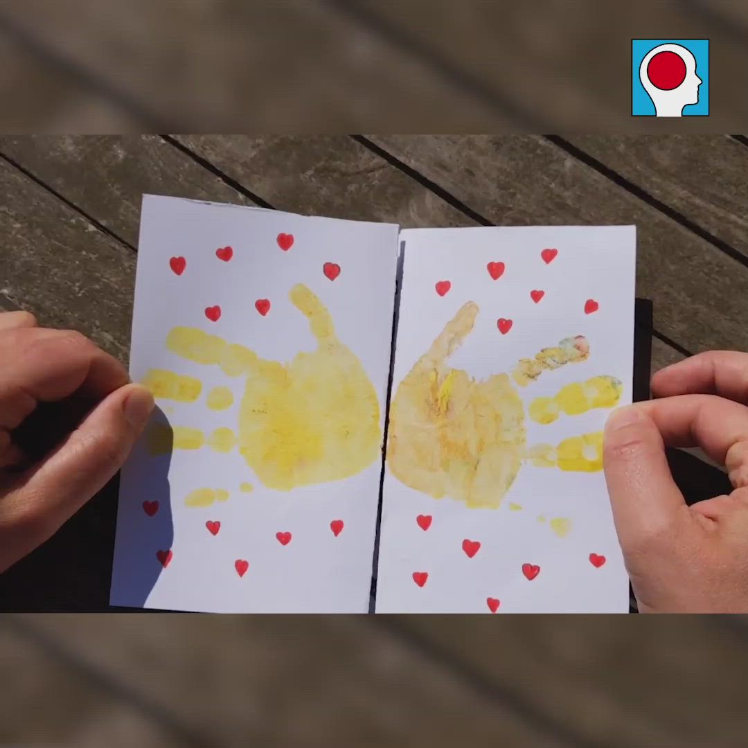 This may contain: two hands holding paper with yellow and red handprints on them next to each other