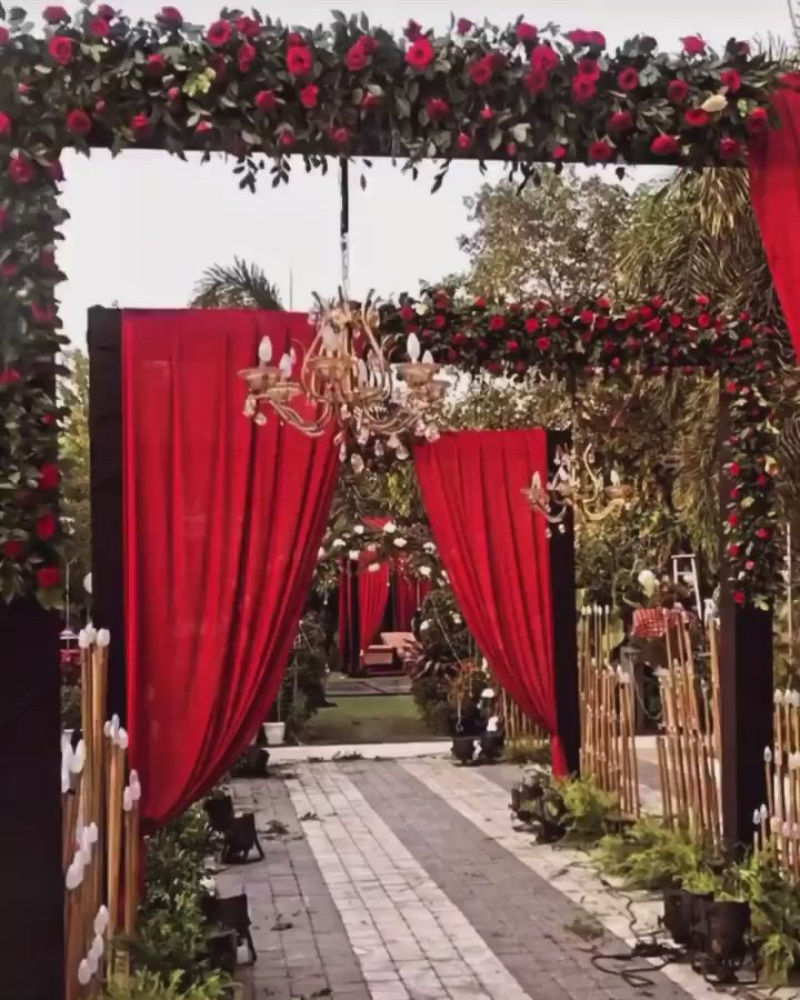 This may contain: an outdoor ceremony with red curtains and flowers