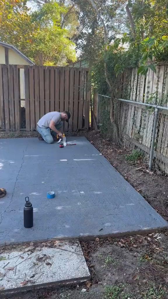 This may contain: a man is laying on the ground in front of a fence with tools and other items