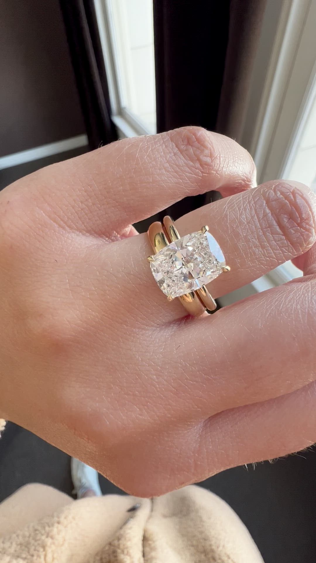 This contains: Video of stunning 3 carat elongated Cushion cut diamond set in a 2mm yellow gold solitaire with a classic basket.  Paired with a comfort fit 4 mm yellow gold wedding band. Shown on hand