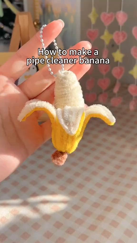 This may contain: a person holding a banana shaped keychain that says how to make a pipe cleaner banana