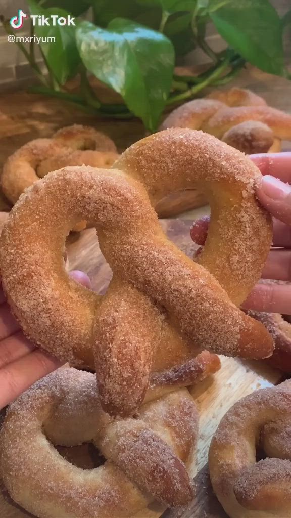 This may contain: two hands holding doughnuts in front of them on a table with other donuts