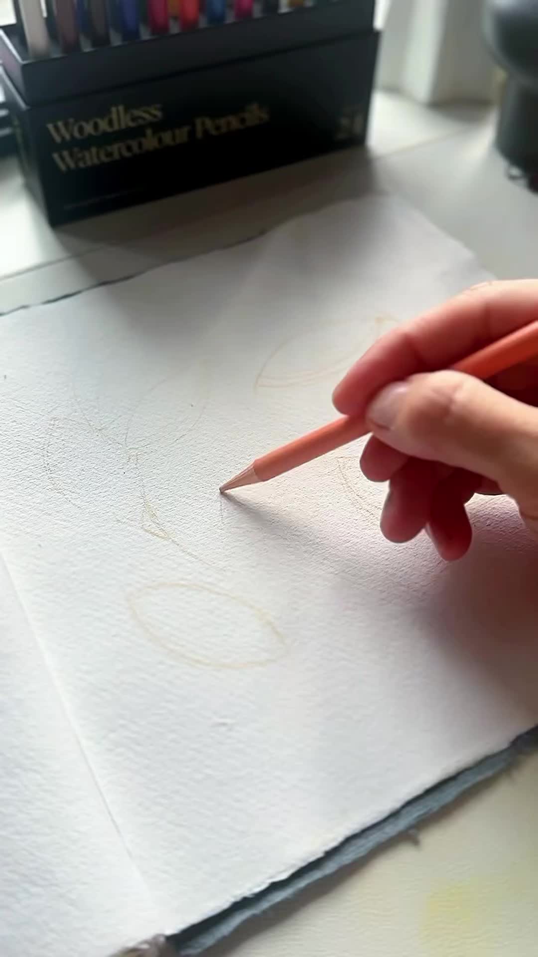 This may contain: a person is drawing on a piece of paper with watercolors in front of them