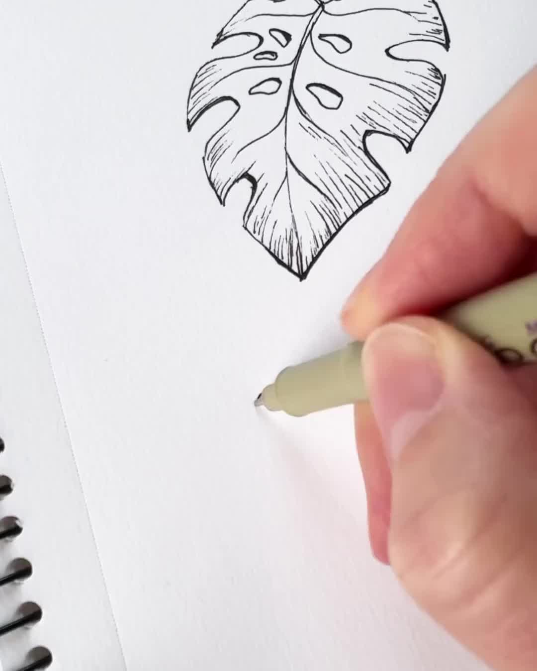 This may contain: a person is drawing a leaf on paper with a marker and pen in their hand