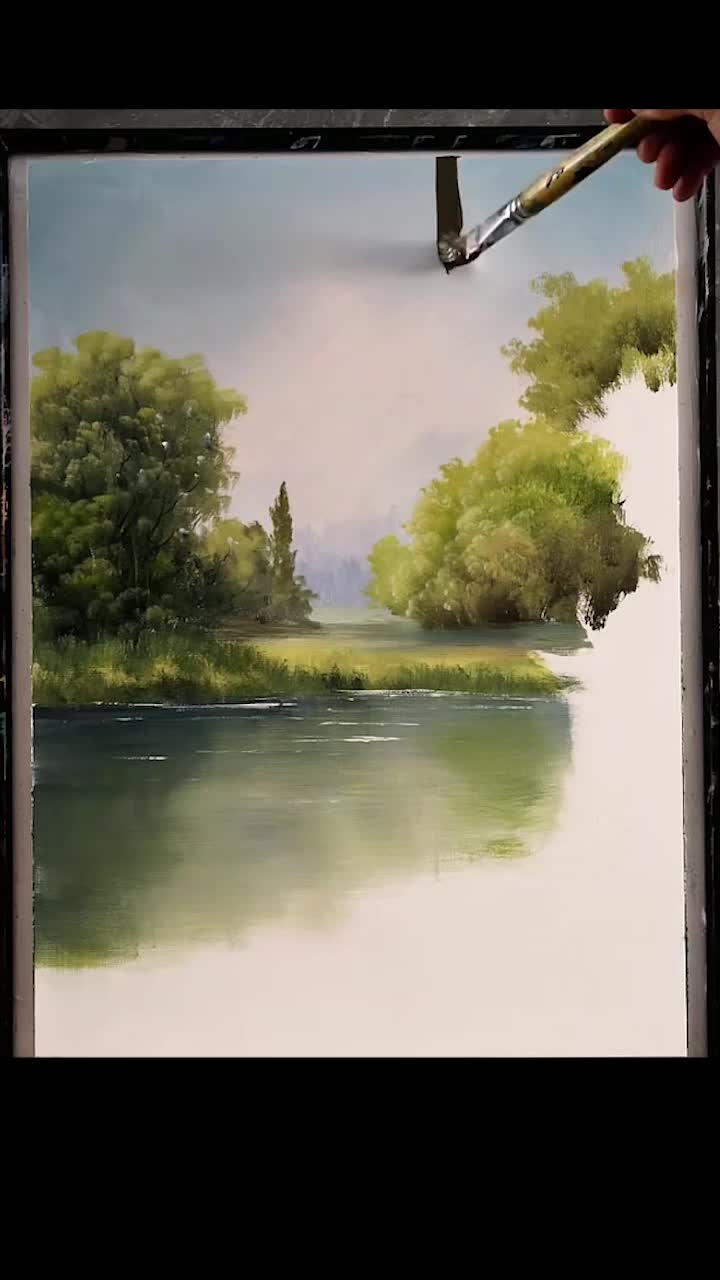 This may contain: a person is holding a paintbrush in front of a painting with trees and water