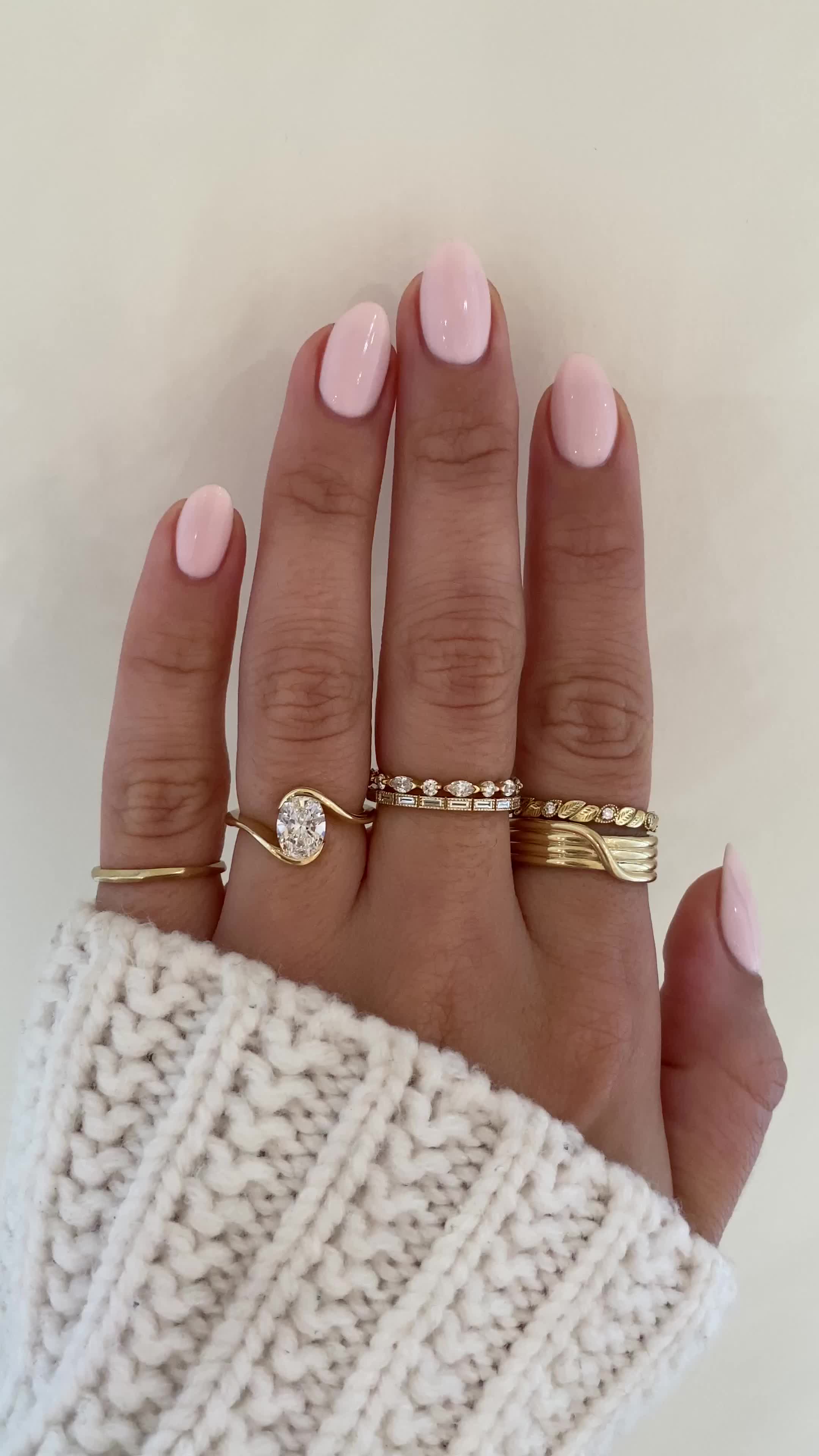 This may contain: a woman's hand with three different rings on her fingers and one is wearing a sweater