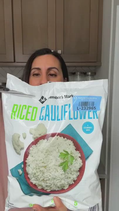 This may contain: a woman holding a bag of rice in front of her face