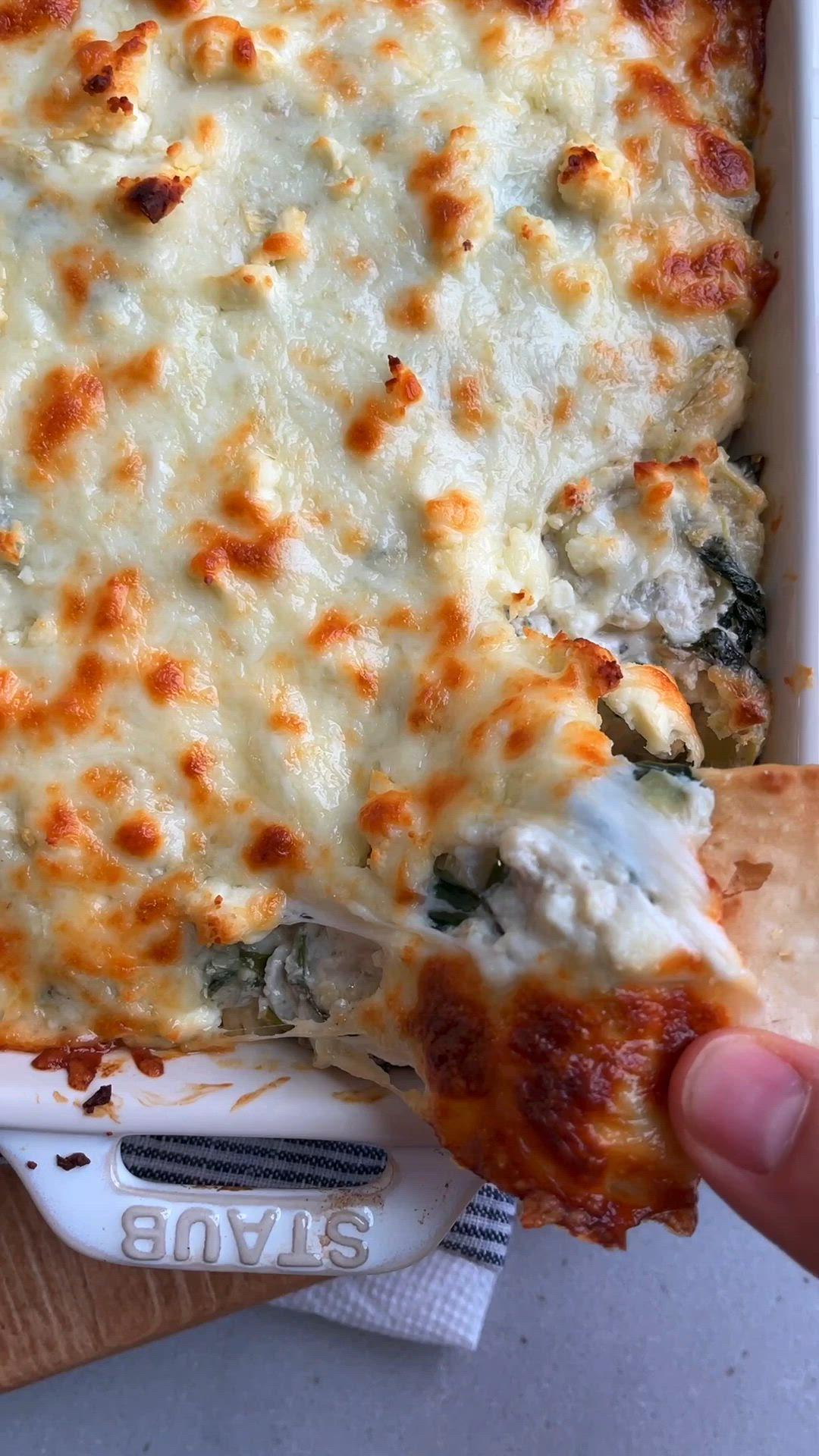 This may contain: a casserole dish with cheese and spinach