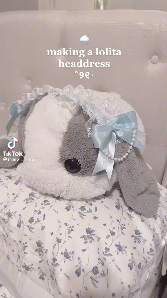 This may contain: a stuffed animal sitting on top of a white chair with a blue bow around it's neck