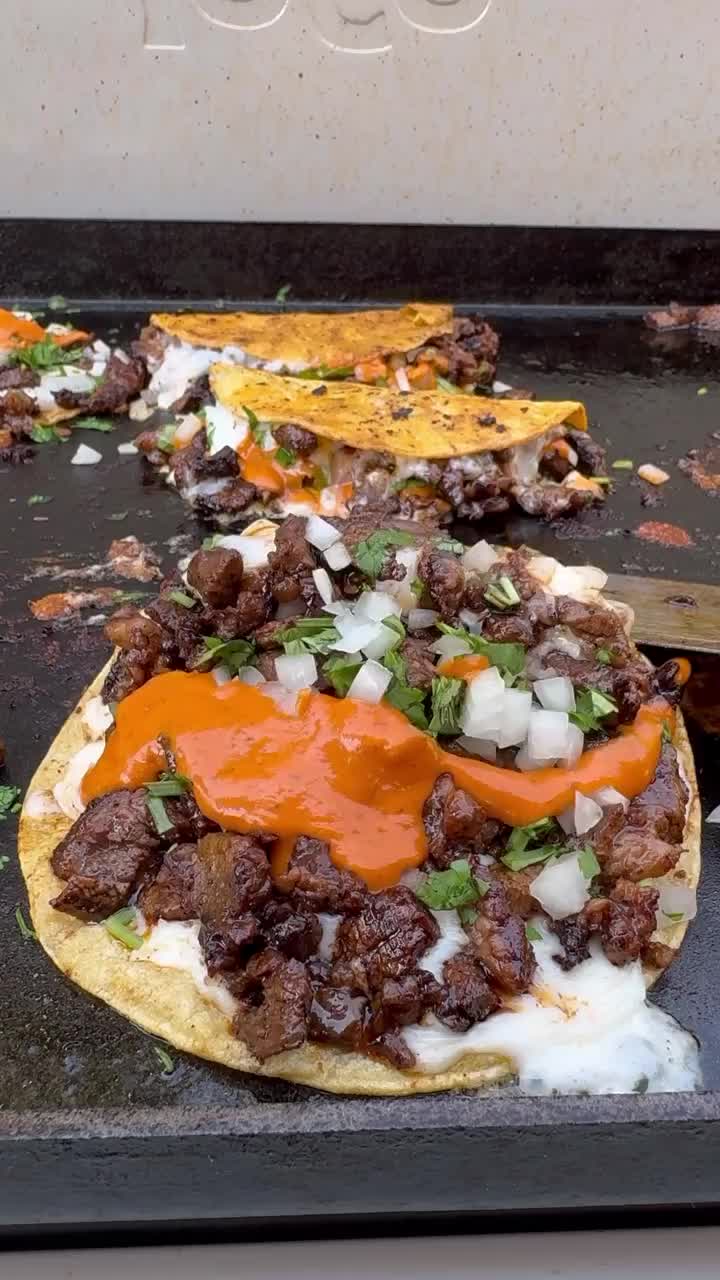 This may contain: an uncooked tortilla sitting on top of a black pan covered in meat and cheese